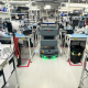 Autonomous vehicle operating between manufacturing workstations while employees carry out production tasks.